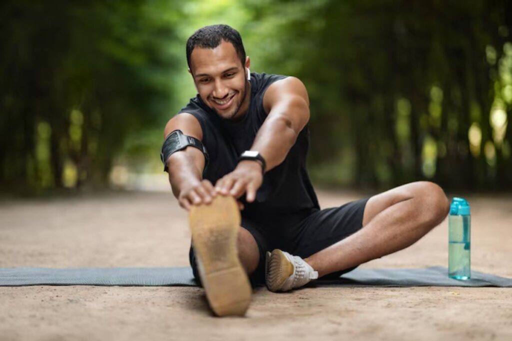 A person stretches on a yoga mat in a green, wooded area, with a water bottle resting nearby.